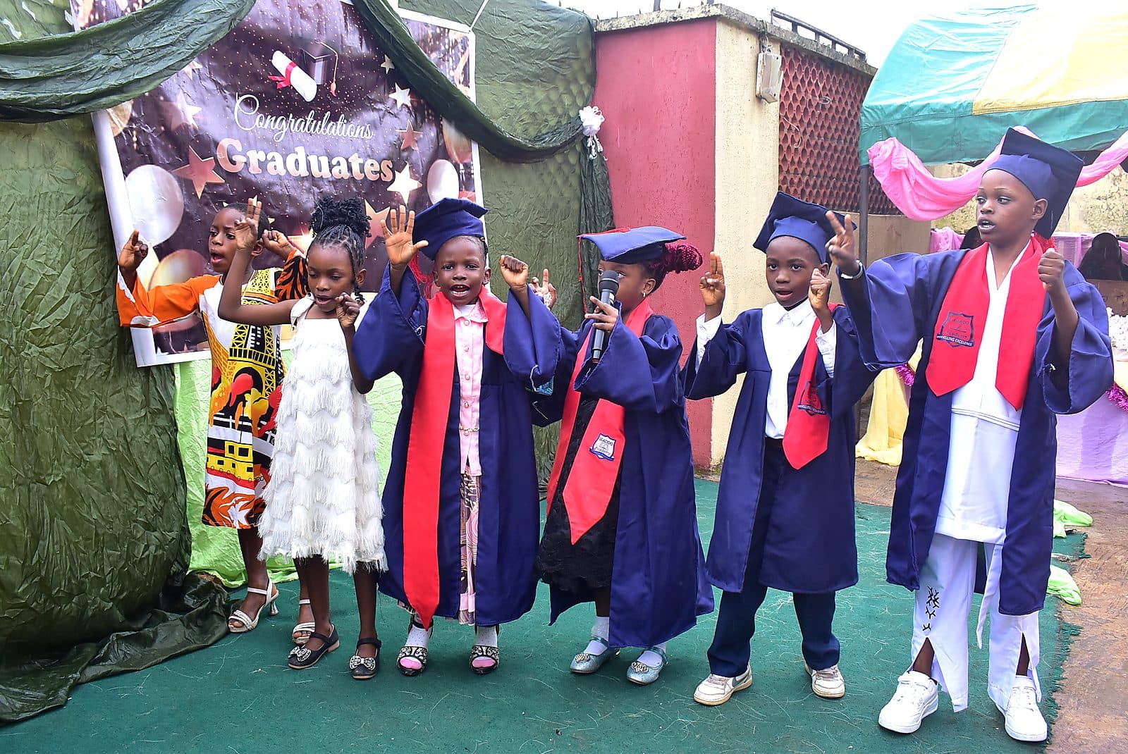 Graduating pupils in caps and gowns cheering after the ceremony