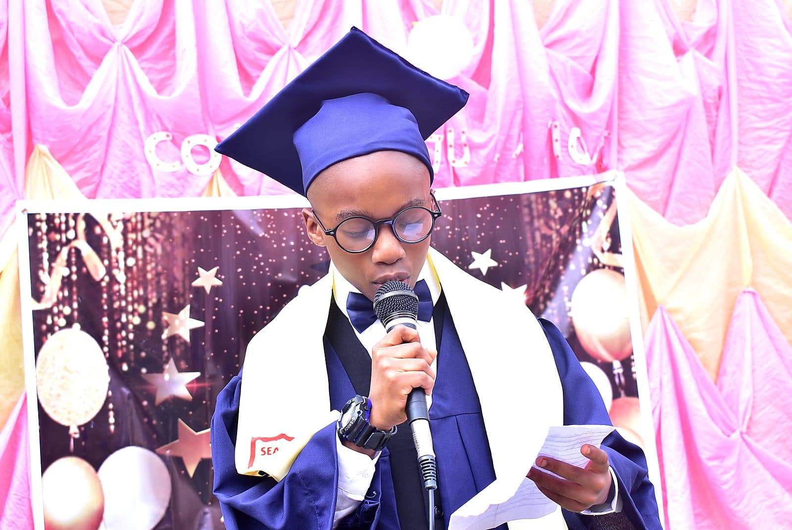A graduating pupil reading his speech at the microphone