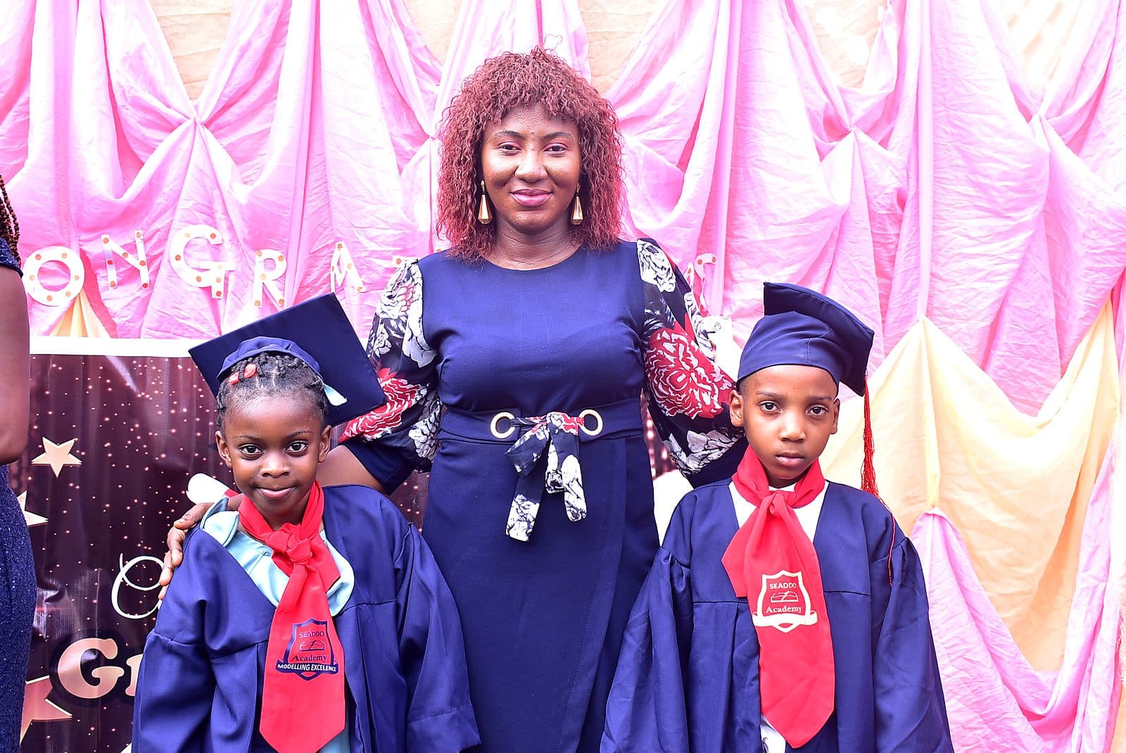 Two graduates photographed with a member of staff after the ceremony