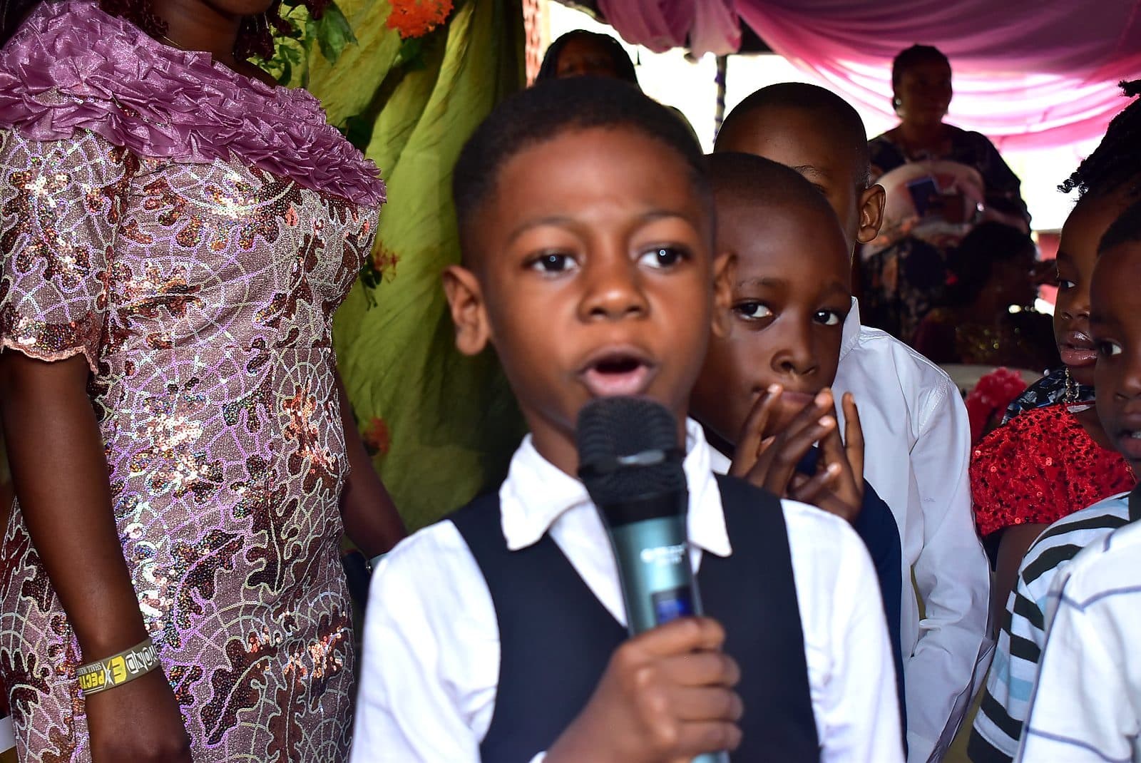 A pupil speaking into the microphone in front of the school